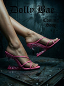 A promotional graphic showing a person's legs wearing pink strappy mule sandals with clear ice-like heels, set against a dark textured background with the text 'Dolly Bae Coming Soon'.